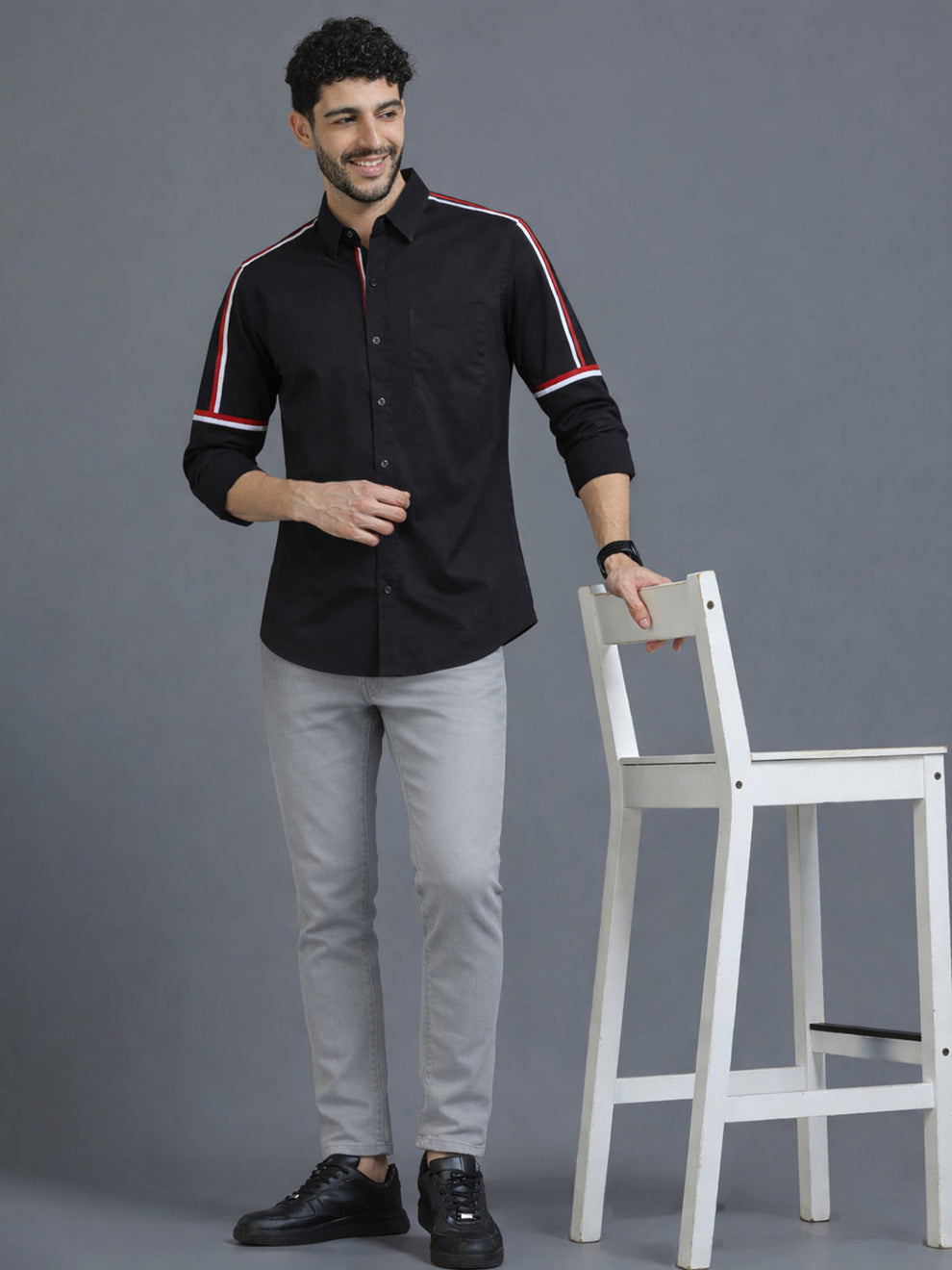Man wearing a black shirt with red and white stripes on a gray background