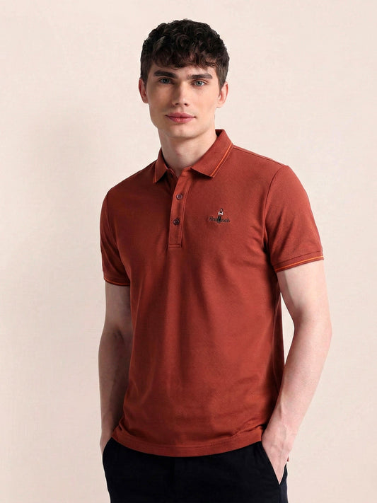 Man wearing a brown polo shirt against a beige background