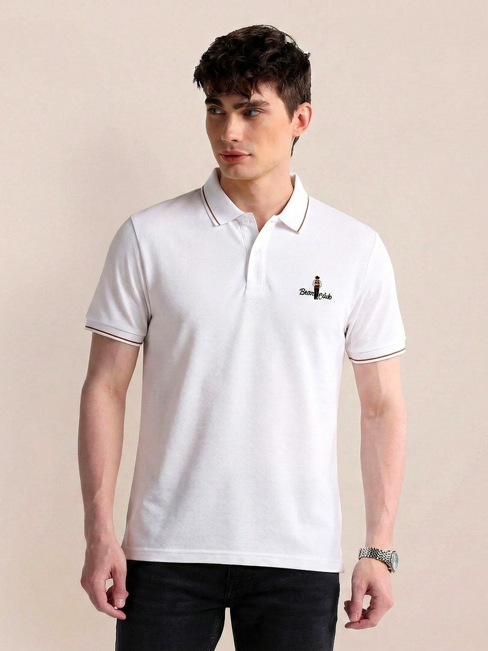 Man wearing a white polo shirt with a logo on a beige background