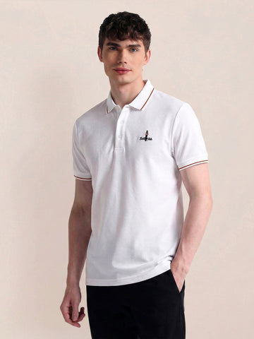 Man wearing a white polo shirt with a logo on a beige background