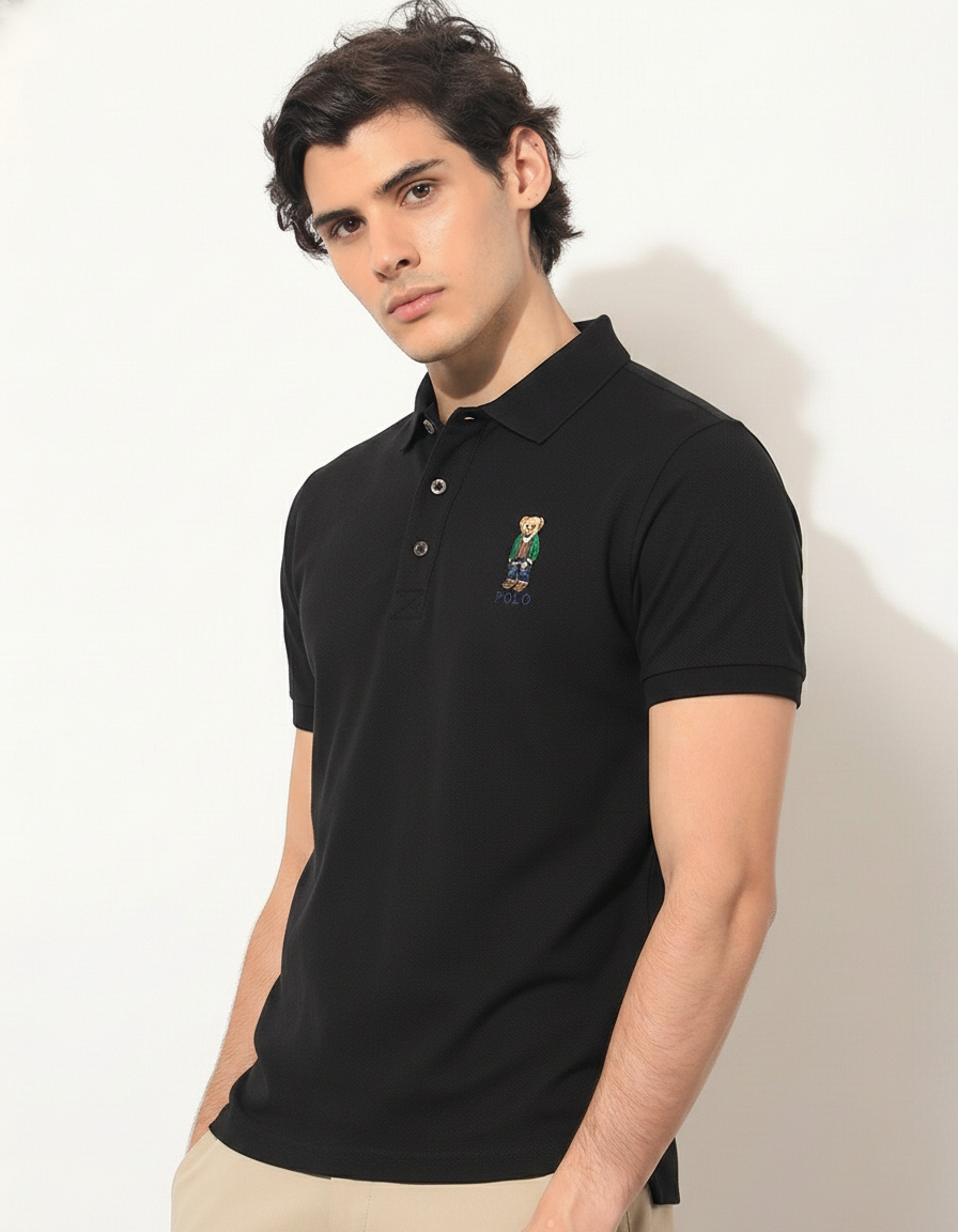 Man wearing a black polo shirt with a small logo on a white background