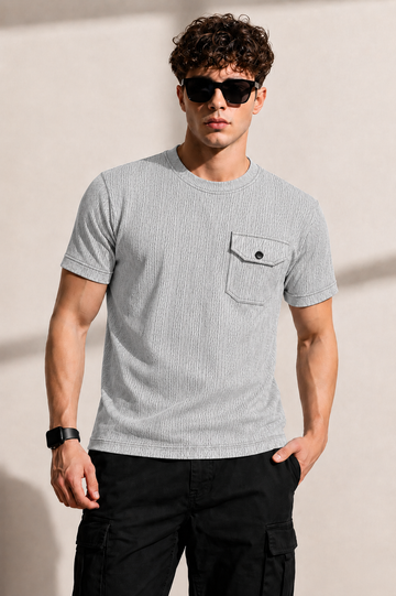Man wearing a gray striped t-shirt and sunglasses against a beige background