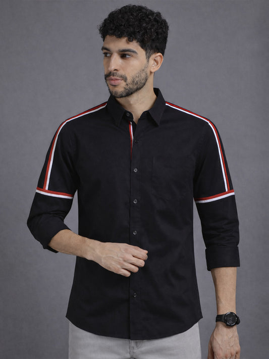 Man wearing a black shirt with red and white stripes on a gray background