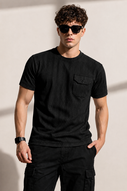 Man wearing a black t-shirt and sunglasses against a plain background
