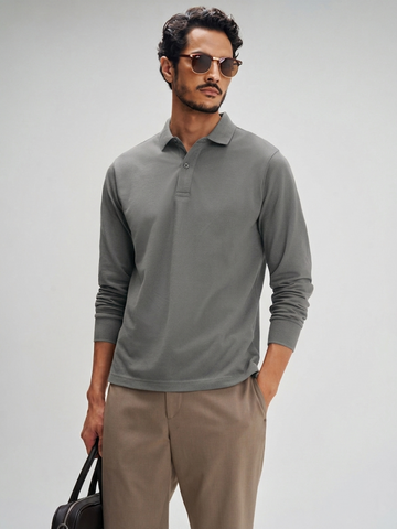 Man wearing a gray long-sleeve polo shirt and beige pants against a plain background