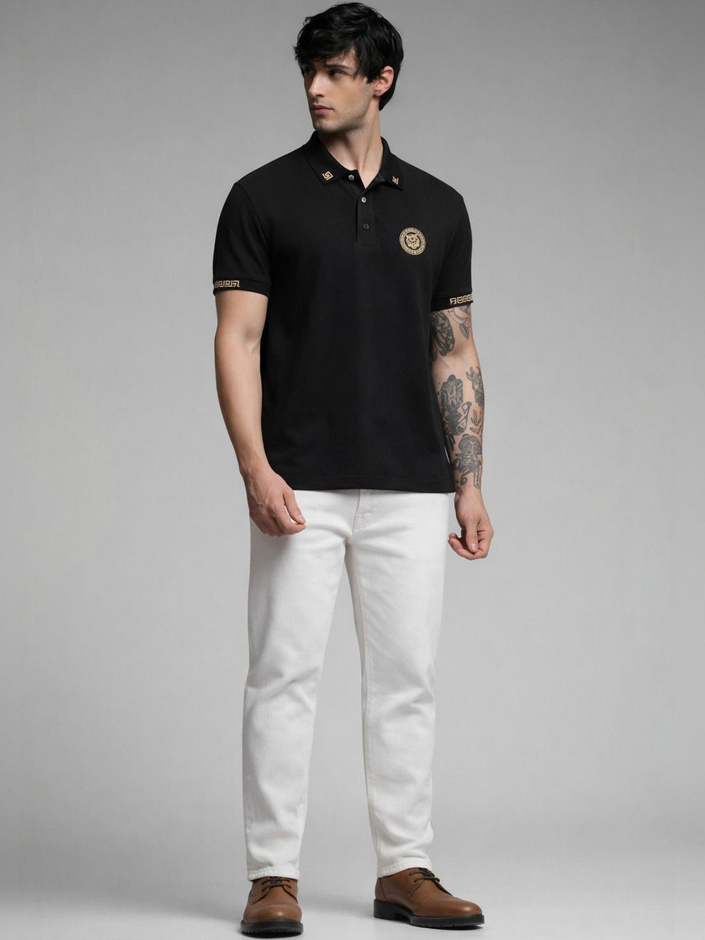Man wearing a black polo shirt with a logo, white pants, and brown shoes on a gray background