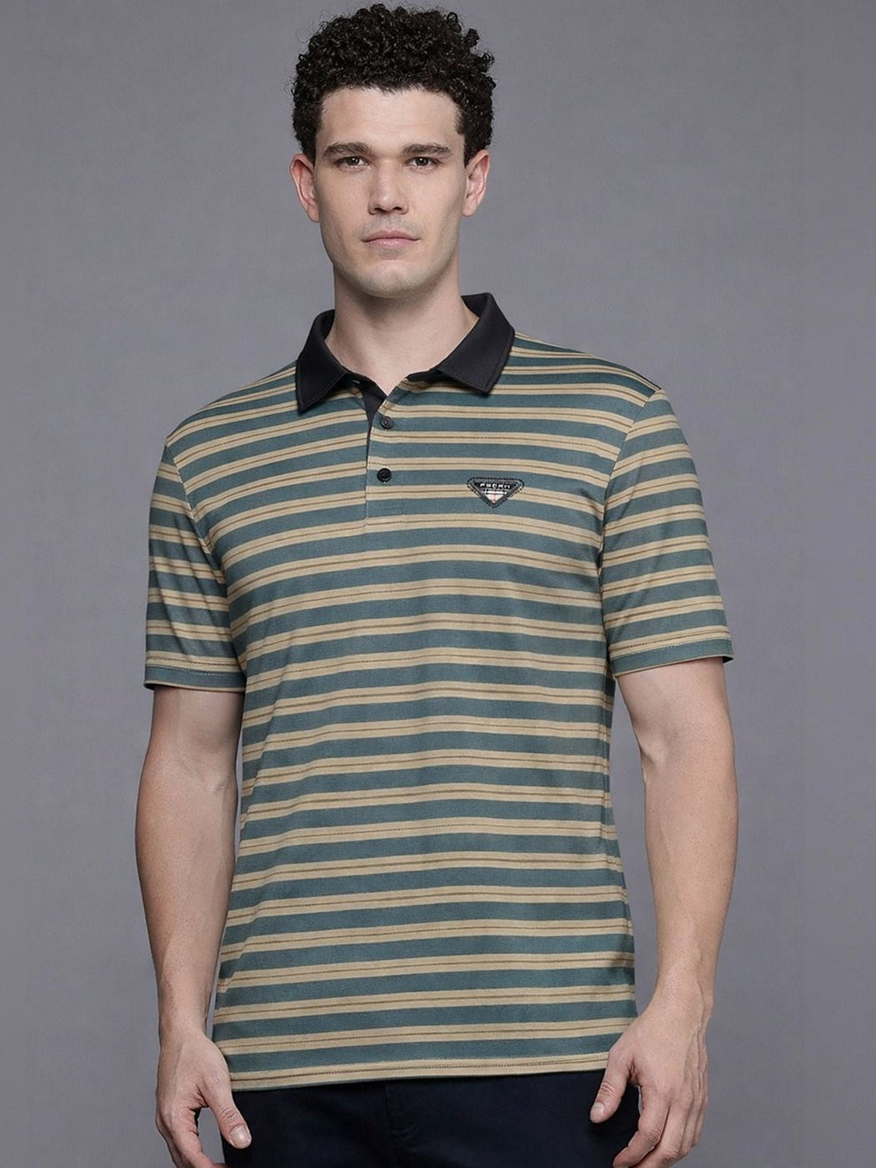 Man wearing a striped polo shirt against a gray background