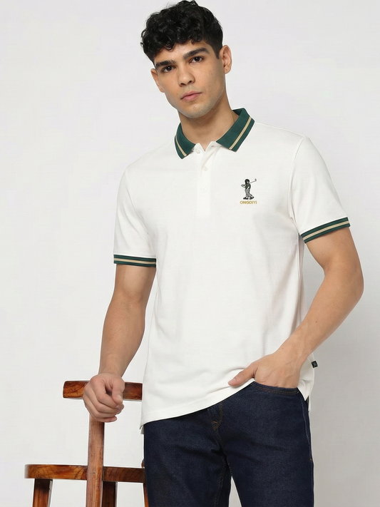 Man wearing a white polo shirt with green accents and dark pants against a plain background