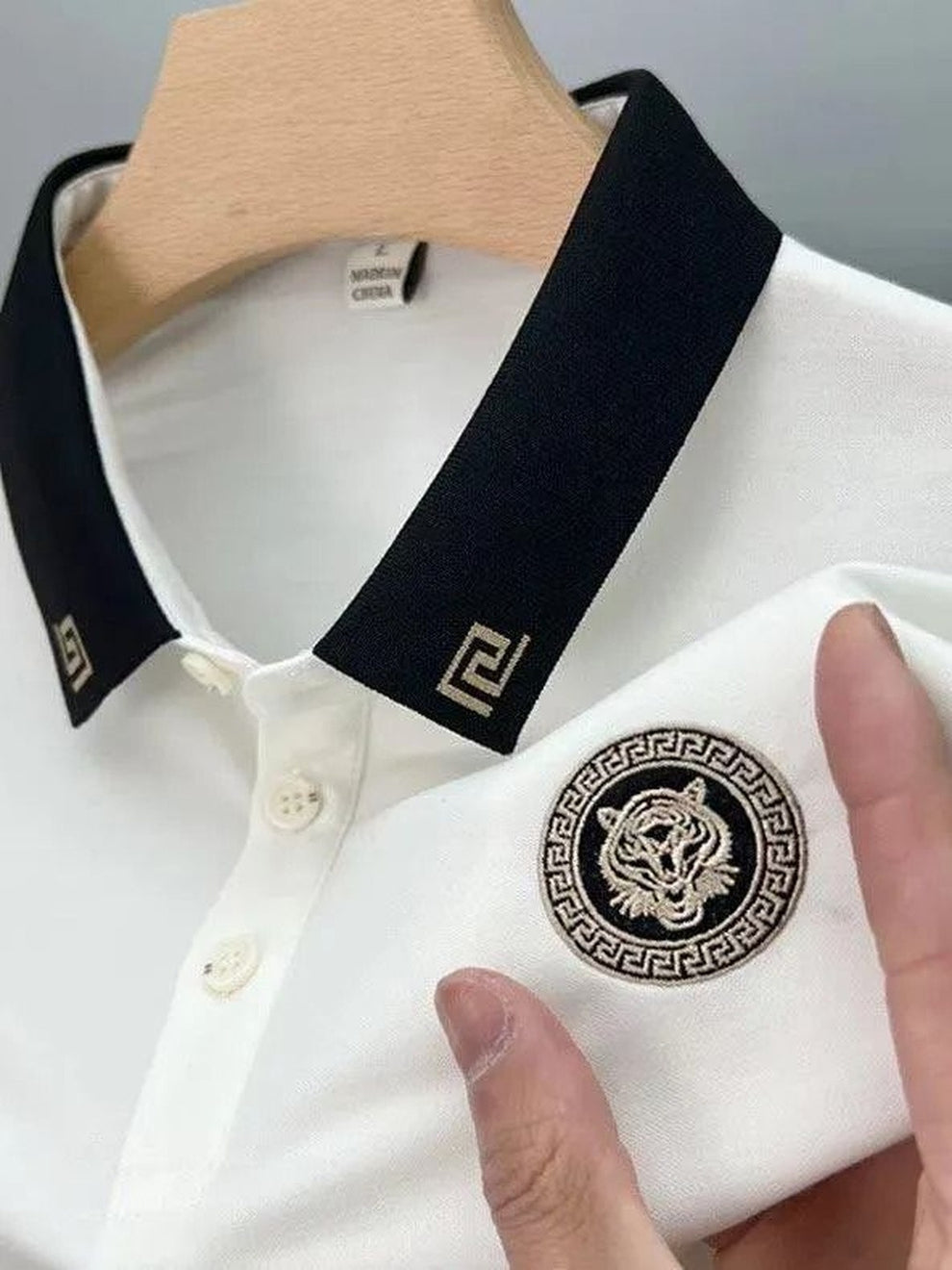 White shirt with black collar and tiger emblem on a hanger