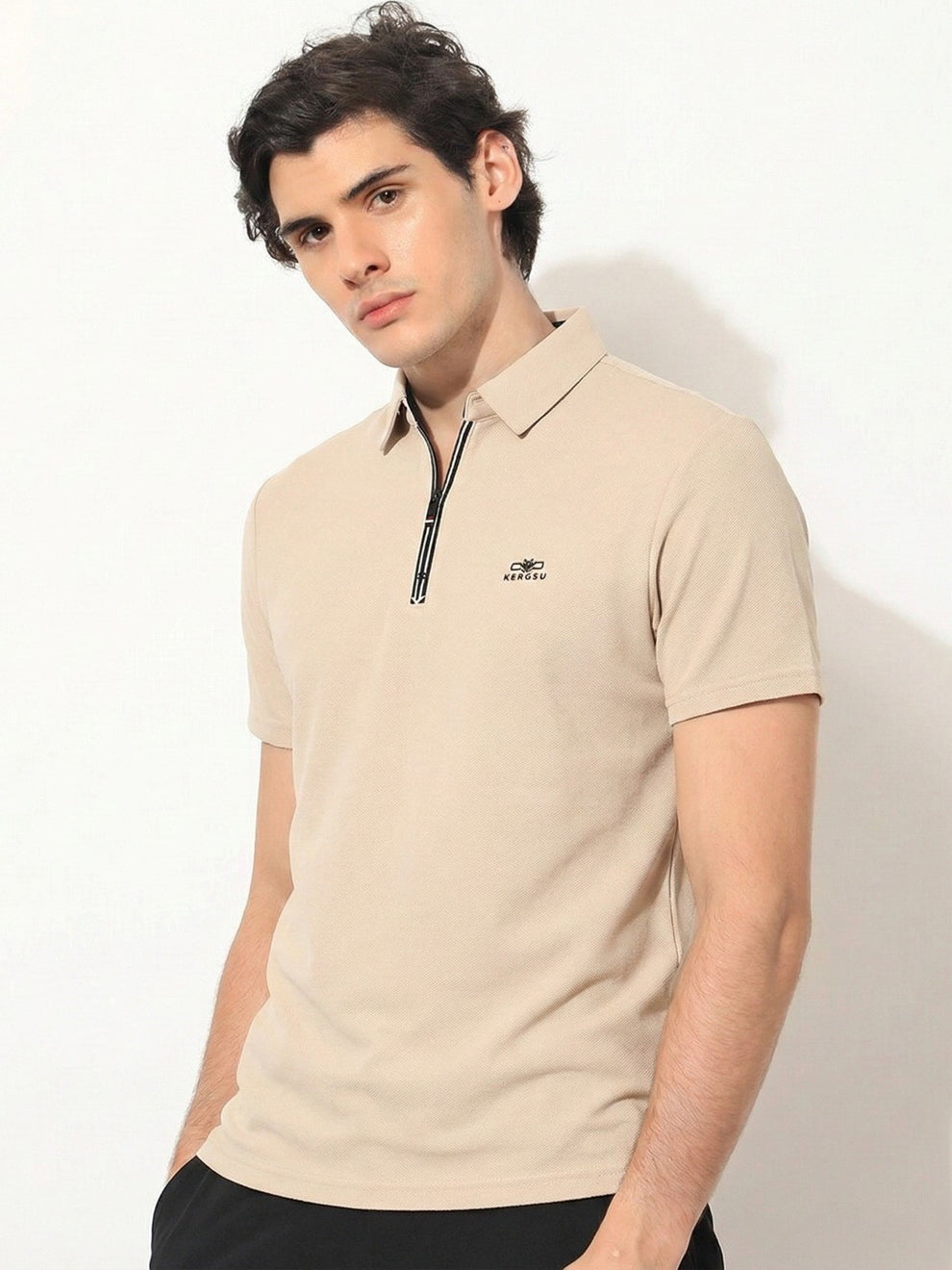 Man wearing a beige polo shirt with a logo on a white background