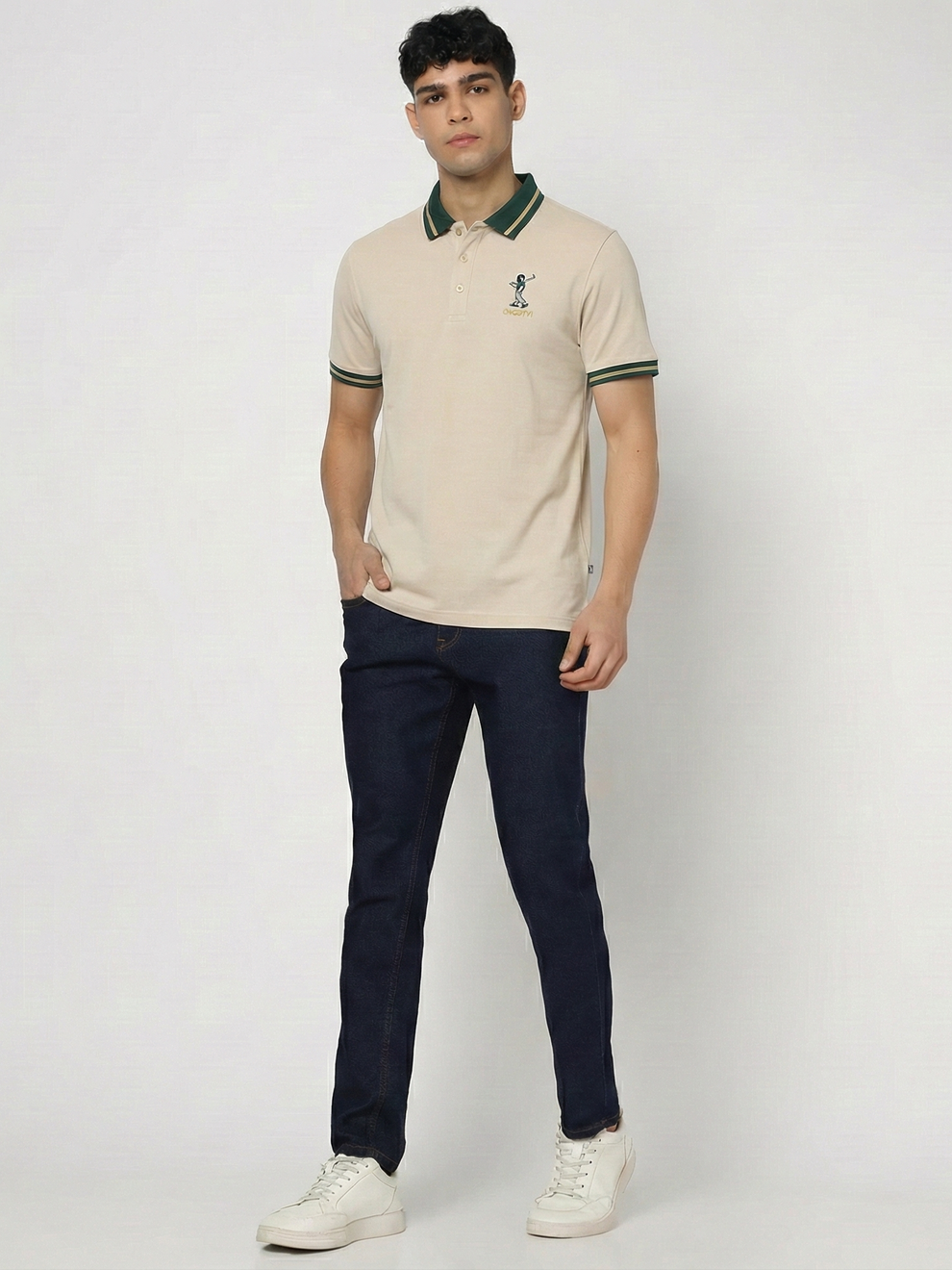 Man wearing a beige polo shirt with green accents and dark pants on a white background