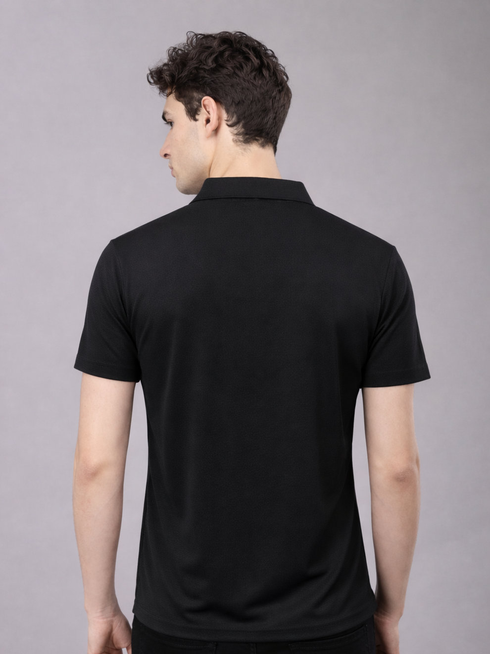 Man wearing a black polo shirt against a gray background