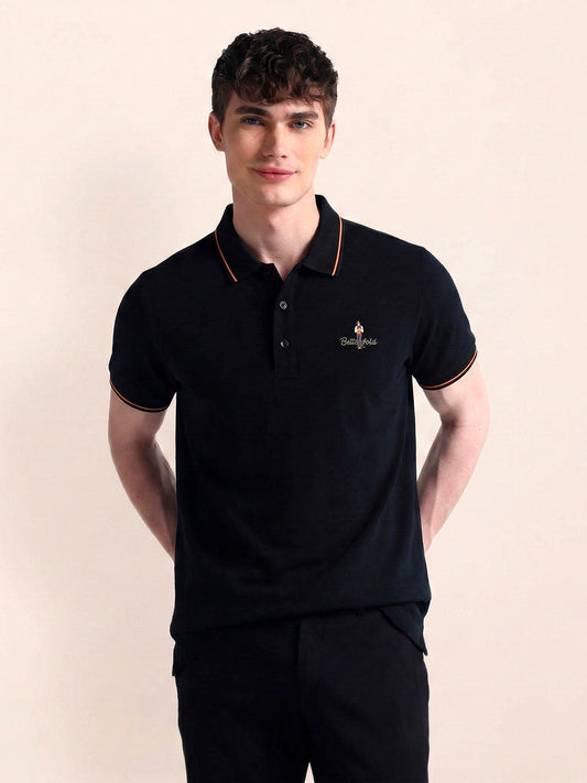 Man wearing a black polo shirt with a logo on a beige background