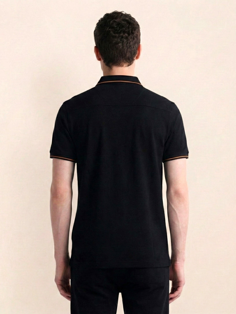 Man wearing a black polo shirt with a beige background