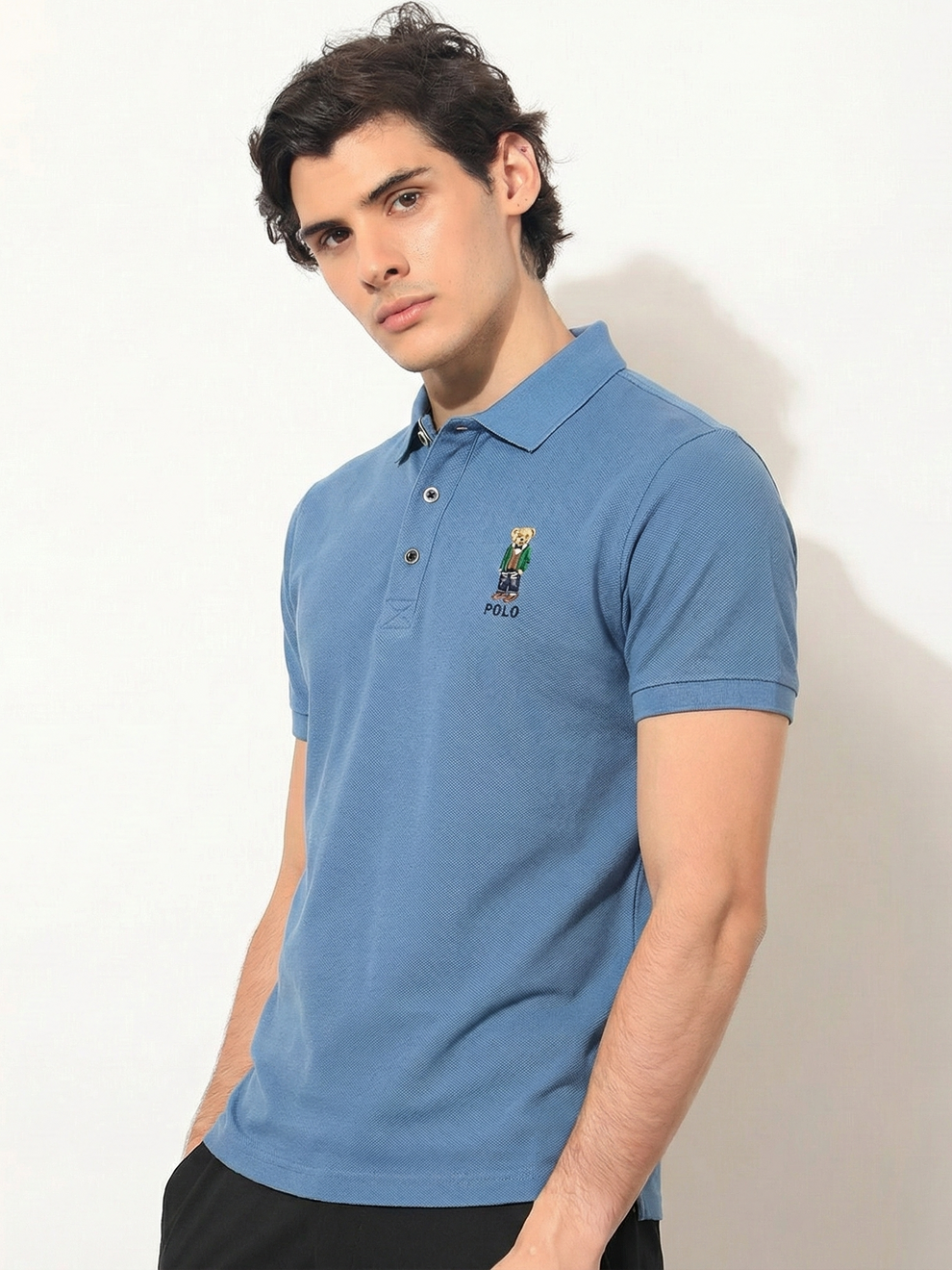 Man wearing a blue polo shirt with a brand logo on a white background