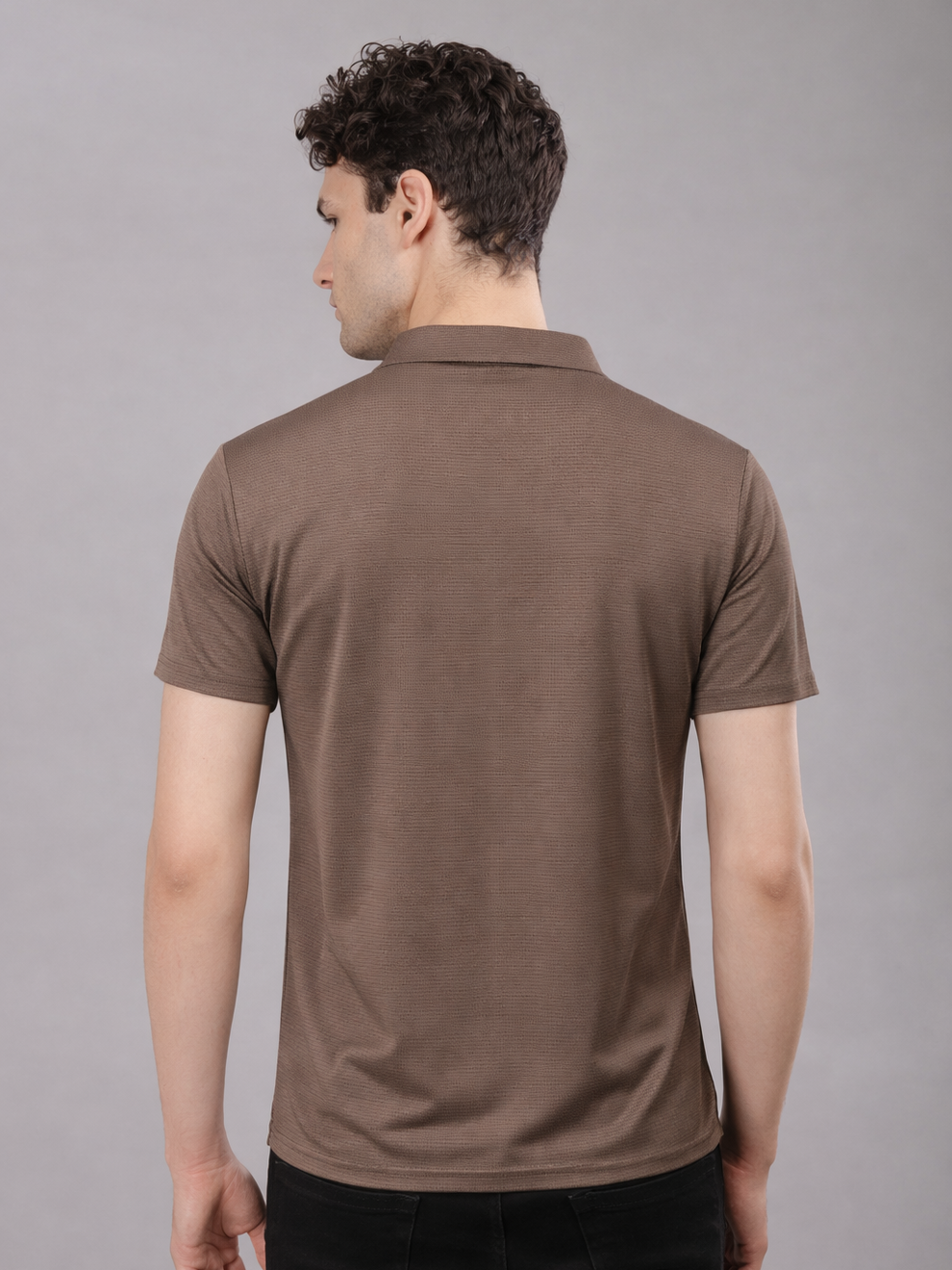 Man wearing a brown polo shirt against a gray background