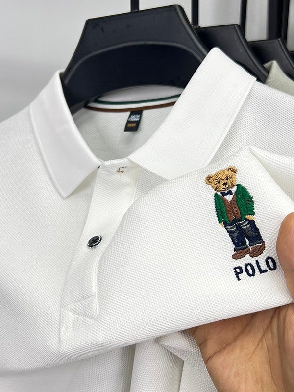 White polo shirt with embroidered bear design and 'Polo' text, held by a hand.