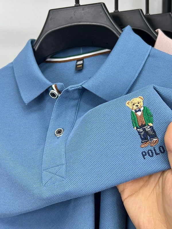 Blue polo shirt with embroidered bear design on a hanger