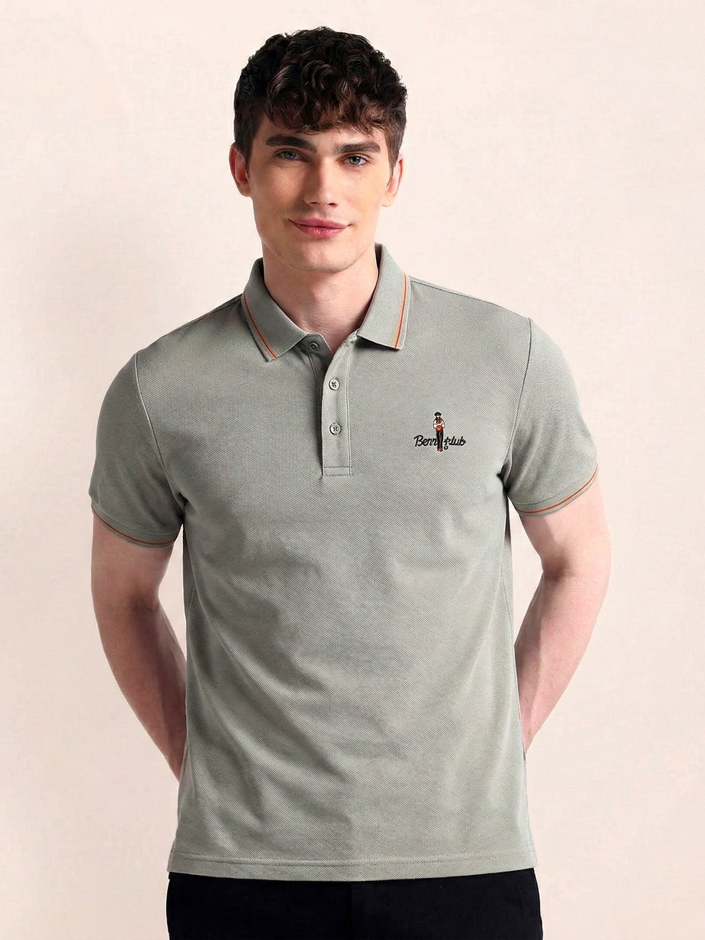 Man wearing a gray polo shirt with a small logo on a beige background