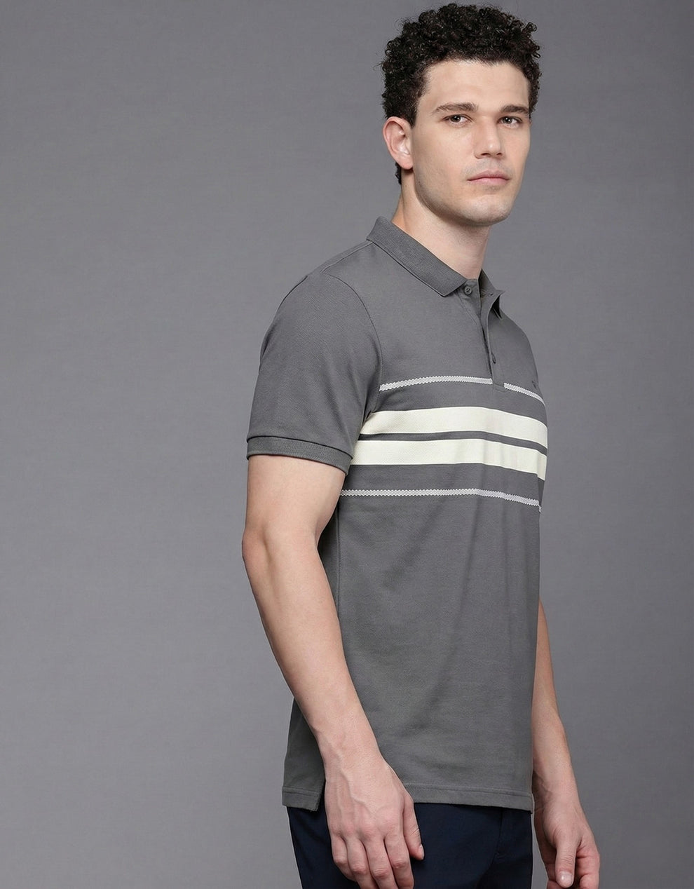 Man wearing a gray polo shirt with white stripes on a gray background