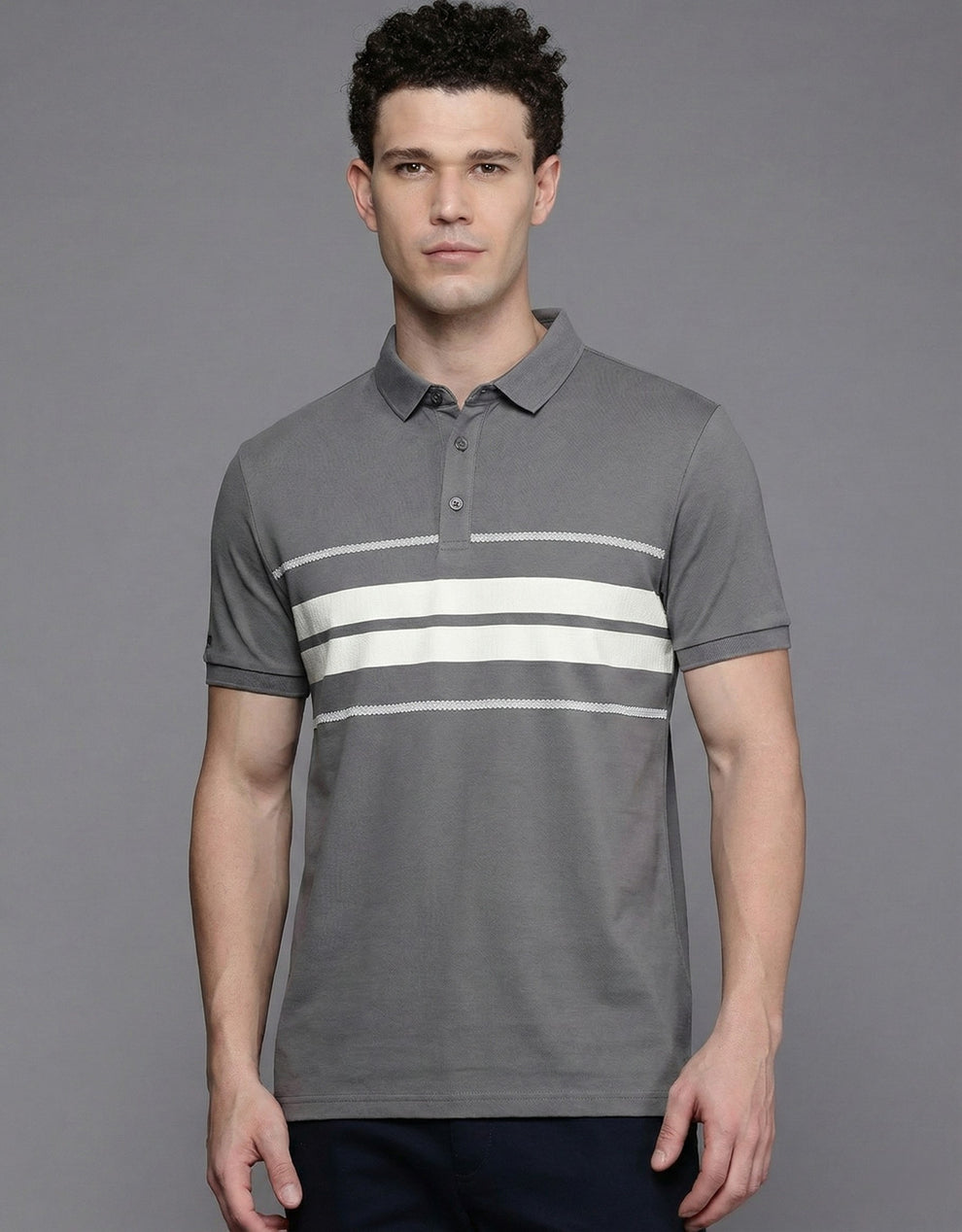 Man wearing a gray polo shirt with white stripes on a gray background