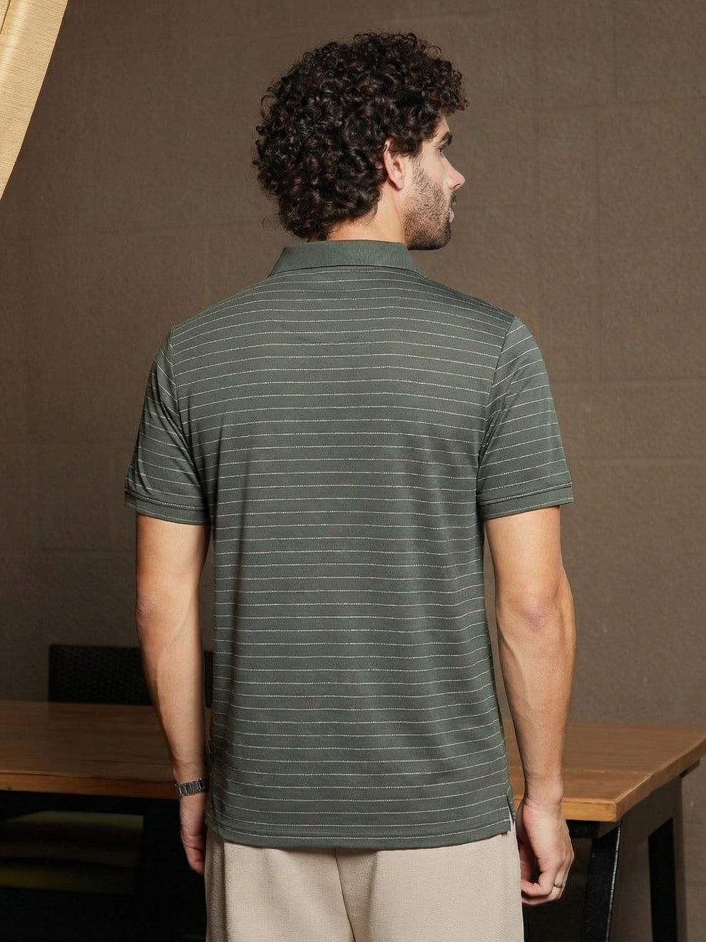 Man wearing a green striped polo shirt in an indoor setting