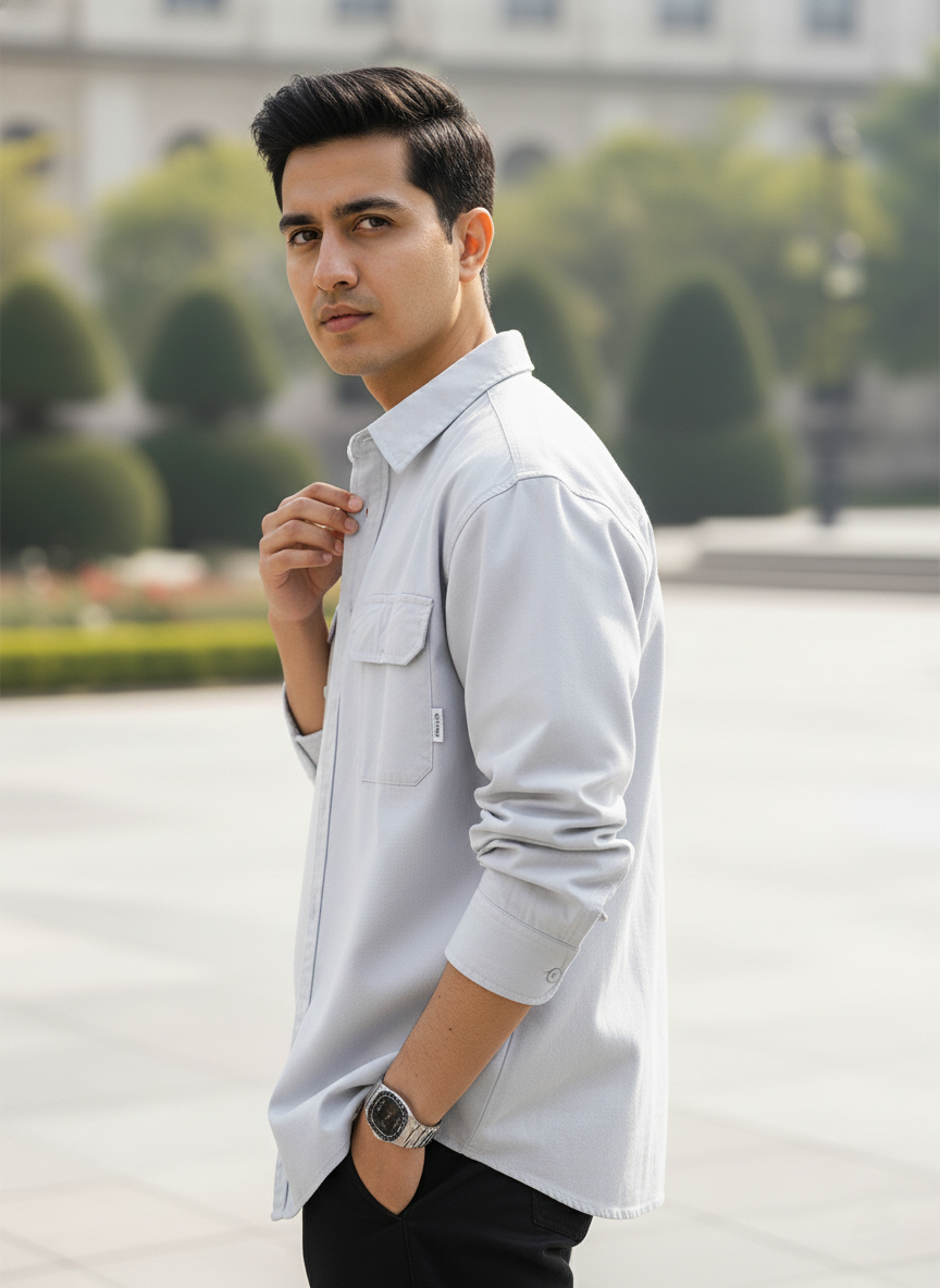 Man wearing a light gray shirt with a blurred outdoor background