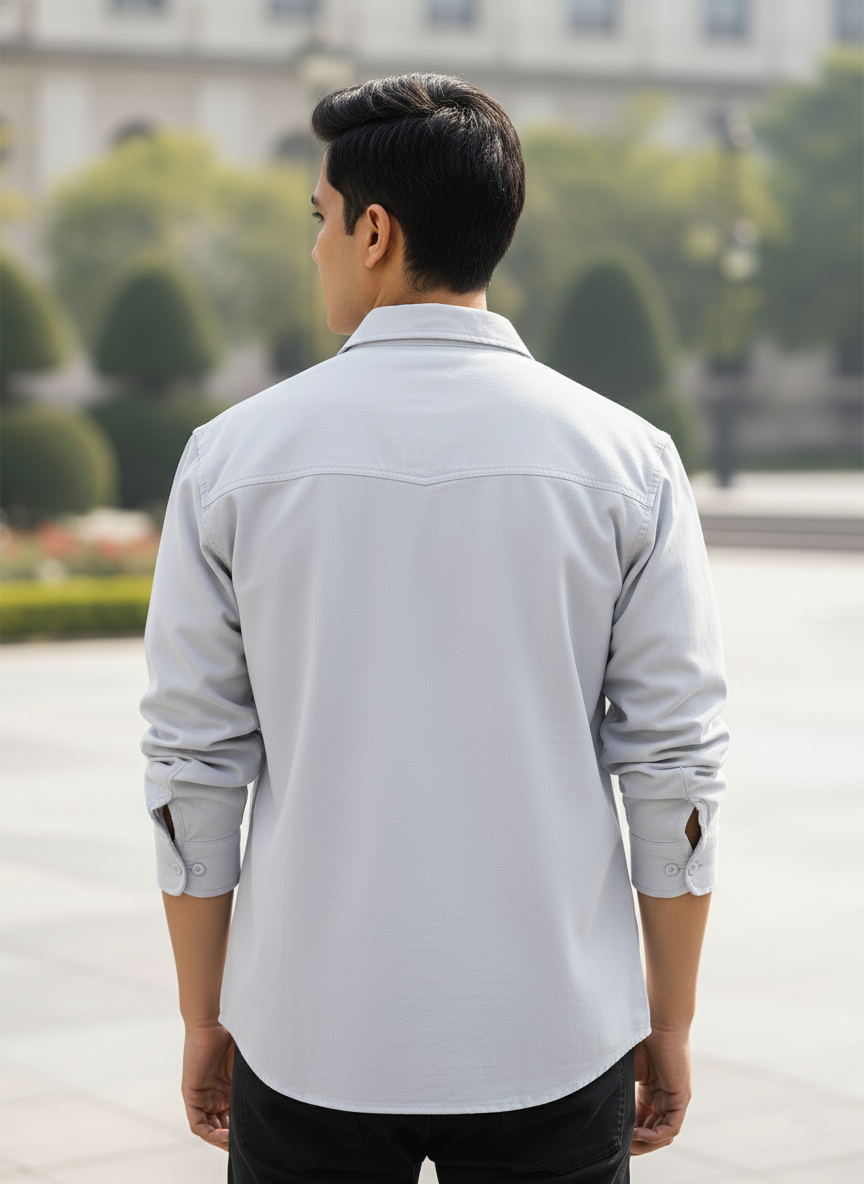 Man wearing a light gray shirt with rolled-up sleeves in an outdoor setting