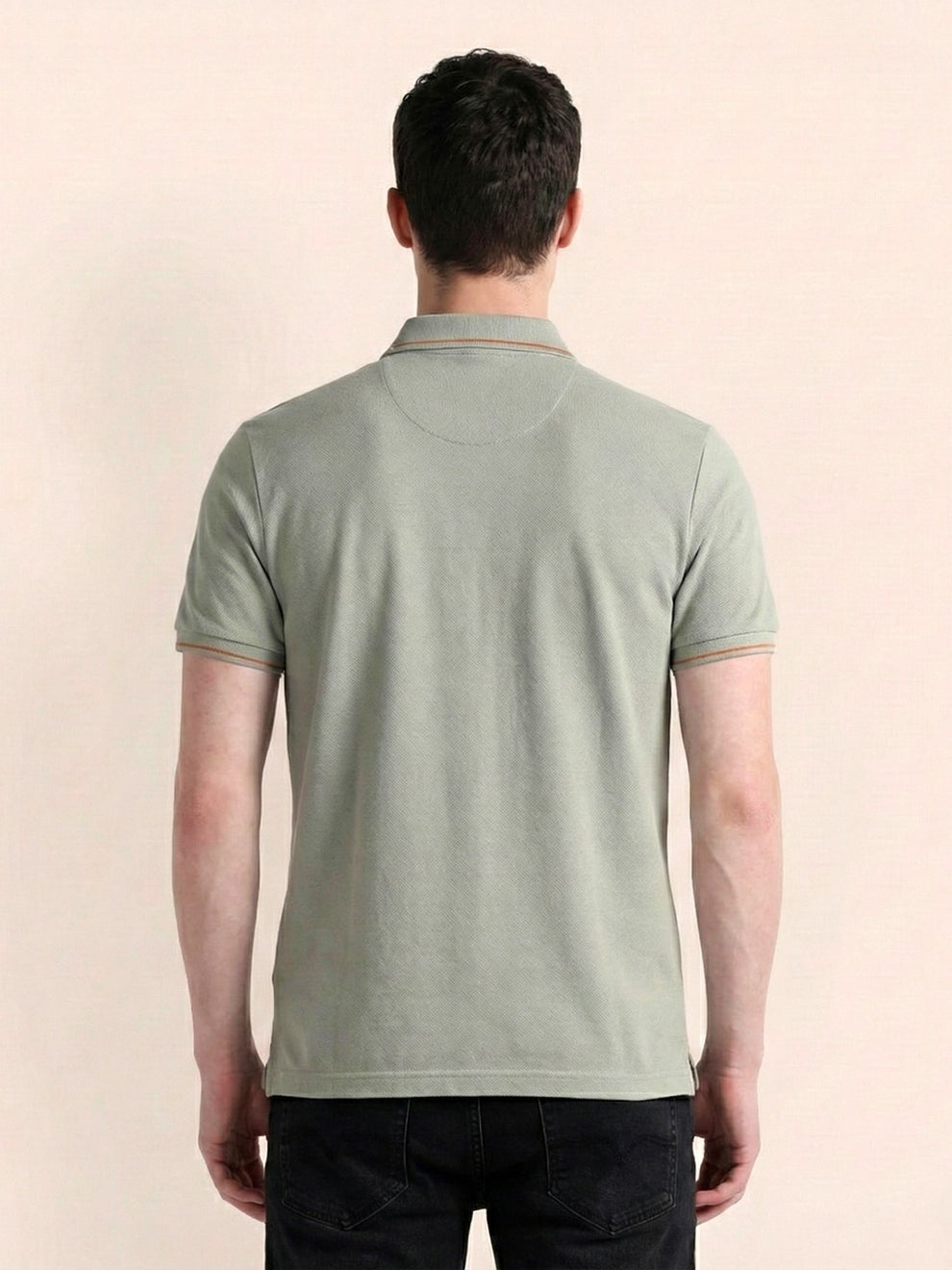 Person wearing a light green polo shirt on a beige background