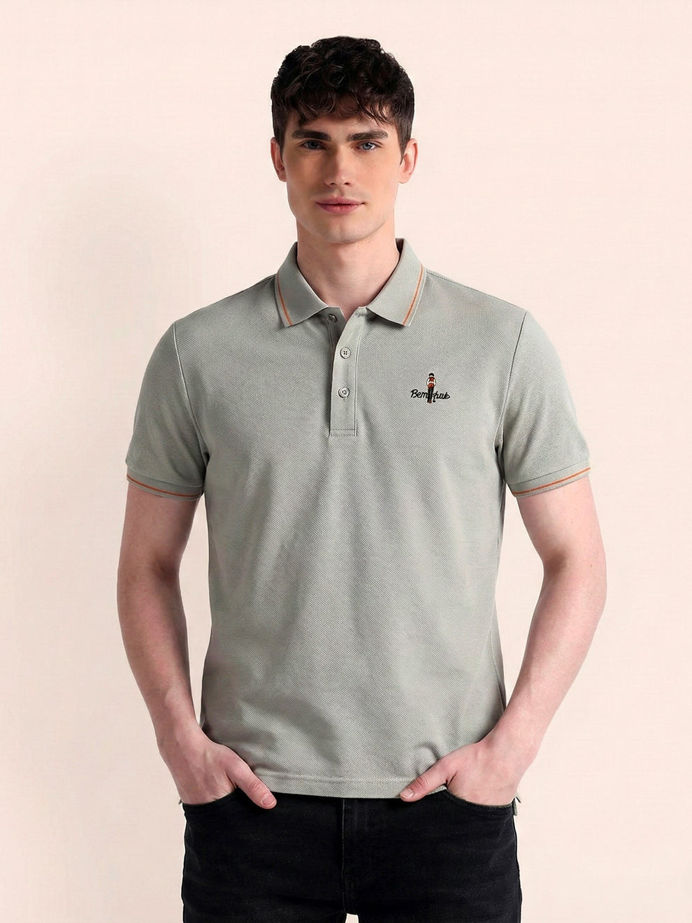 Man wearing a light green polo shirt with a small logo on a beige background