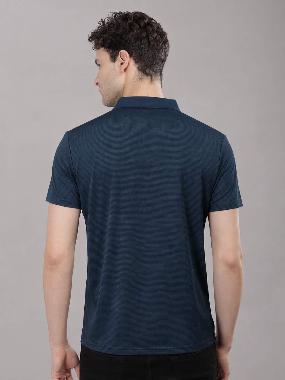 Man wearing a navy blue polo shirt against a gray background