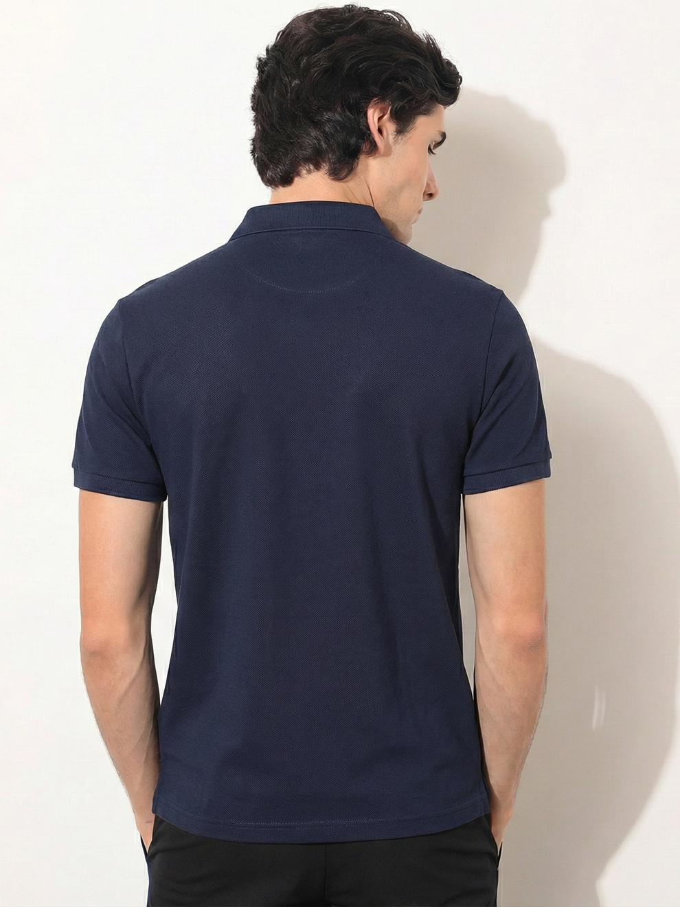 Man wearing a navy blue polo shirt against a white background