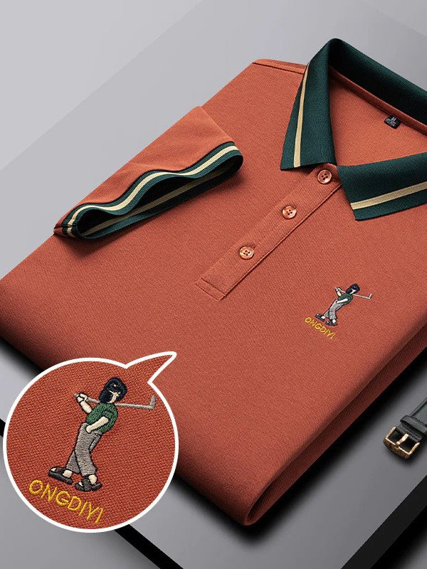 orange polo shirt with green collar and embroidered design on a gray background