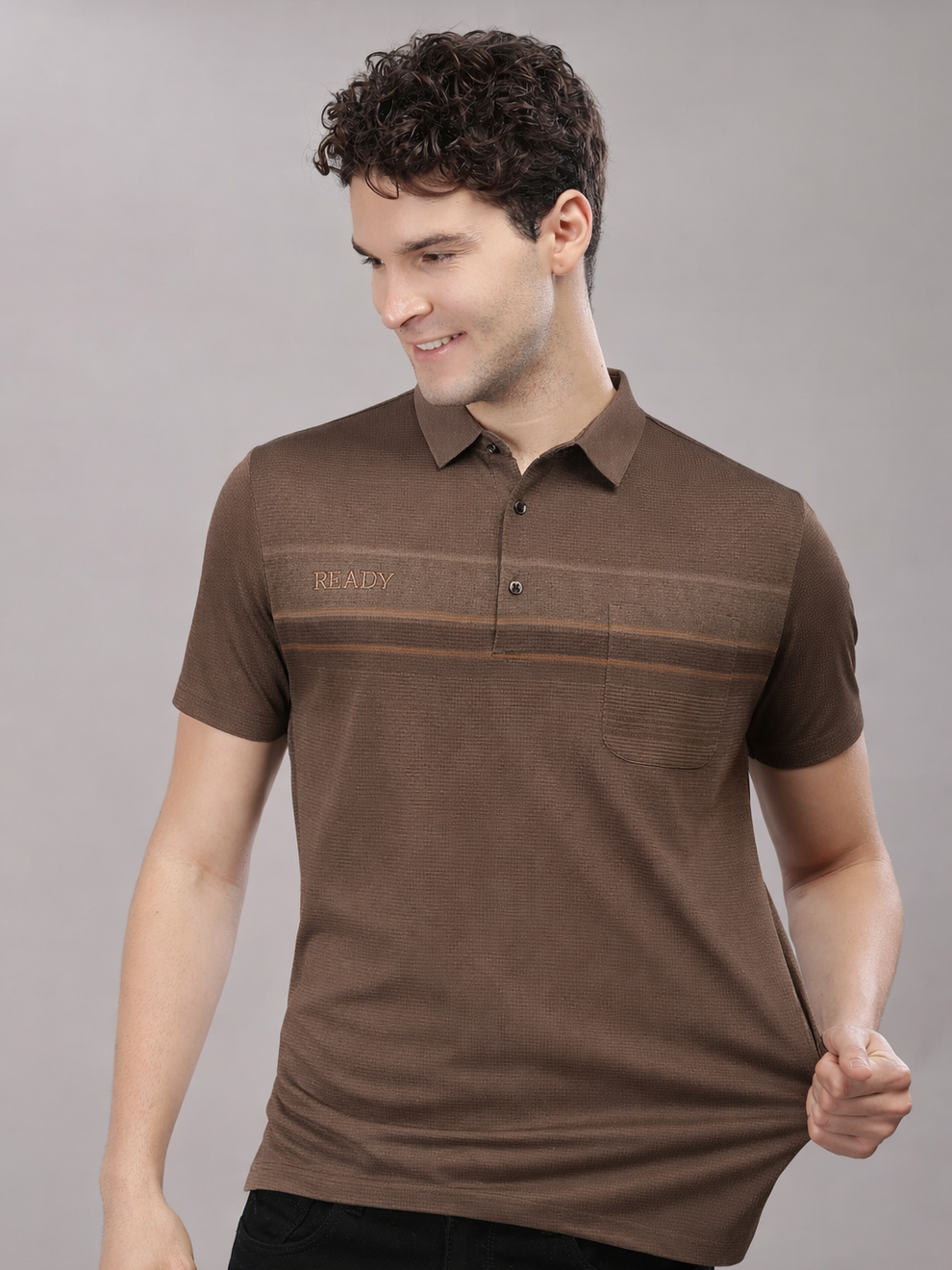 Man wearing a brown polo shirt with a visible brand logo on a gray background