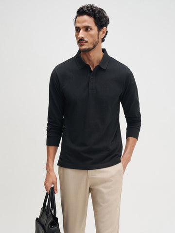 Man wearing a black long-sleeve polo shirt, beige pants, and black shoes on a white background