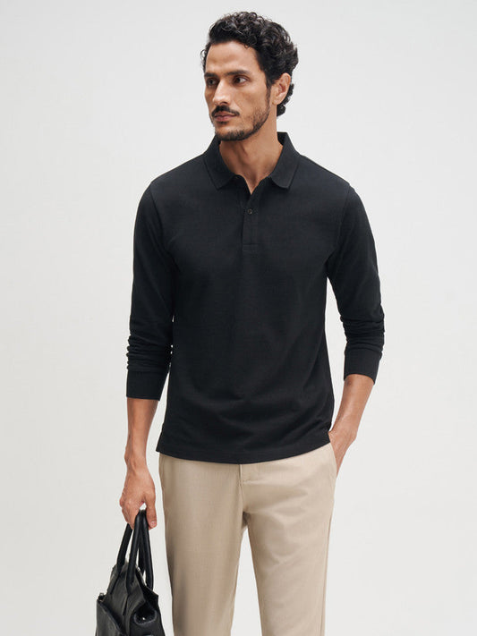 Man wearing a black long-sleeve polo shirt, beige pants, and black shoes on a white background