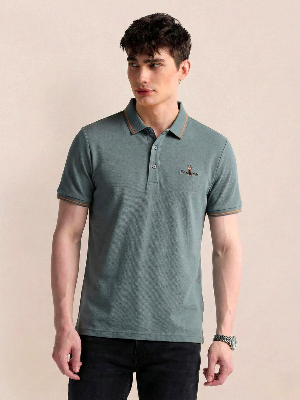Man wearing a green polo shirt with a small logo on a beige background