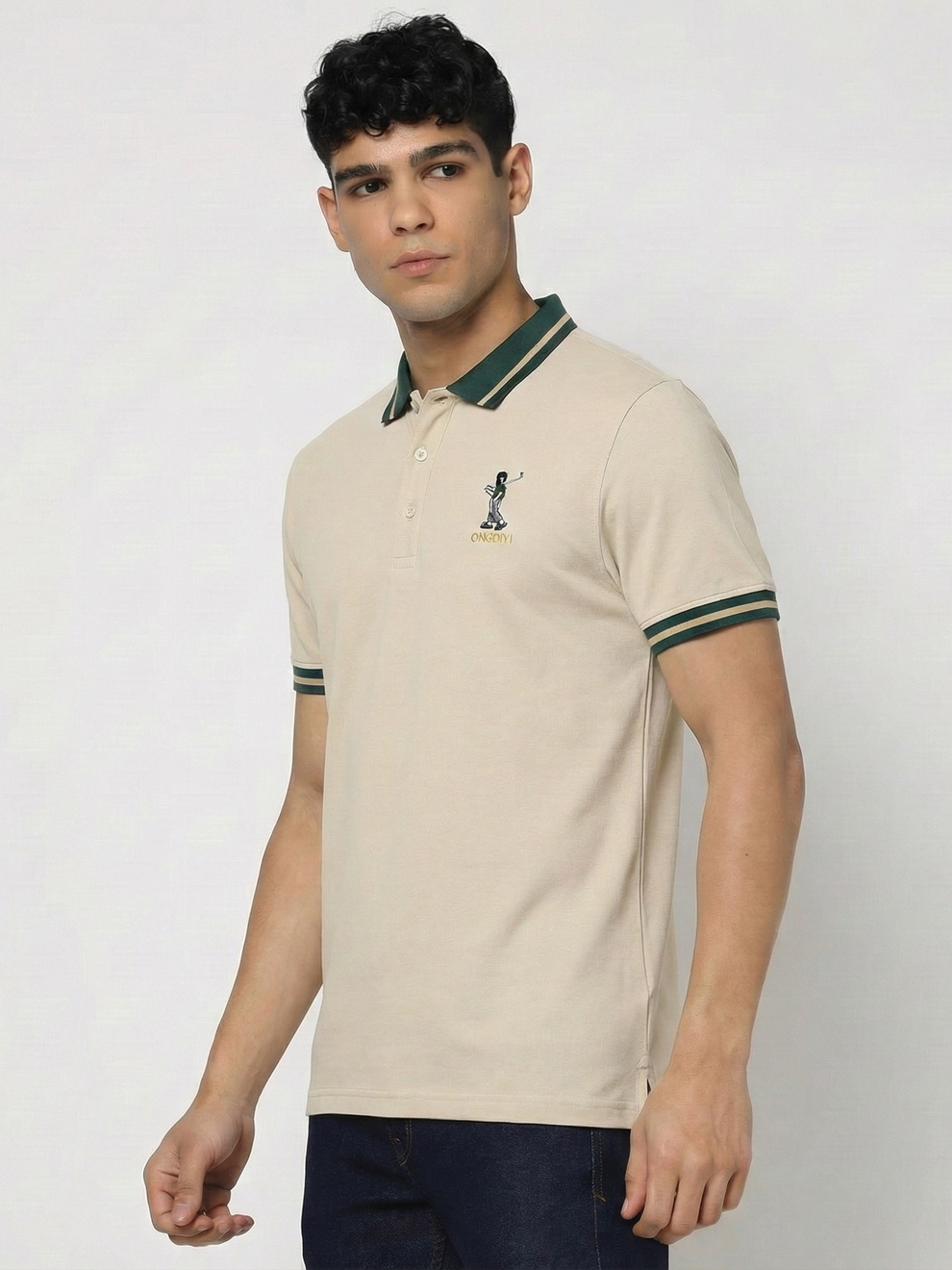 Man wearing a beige polo shirt with green accents on a white background