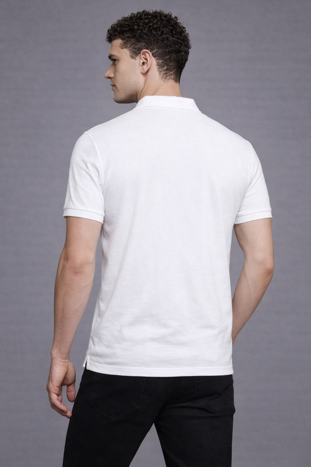 Man wearing a white polo shirt against a gray background