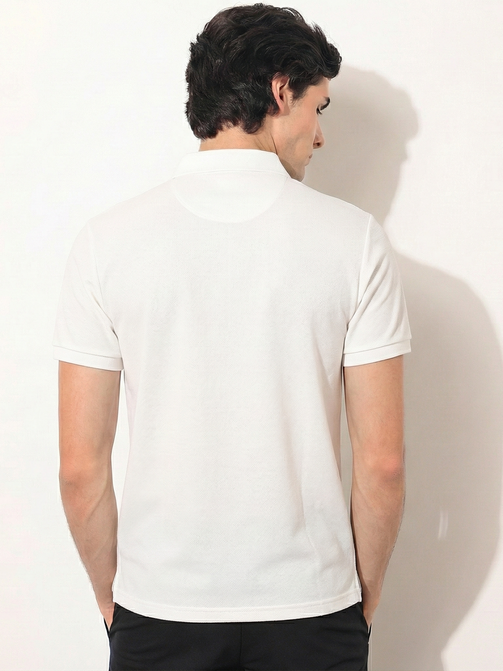 Man wearing a white polo shirt against a plain background