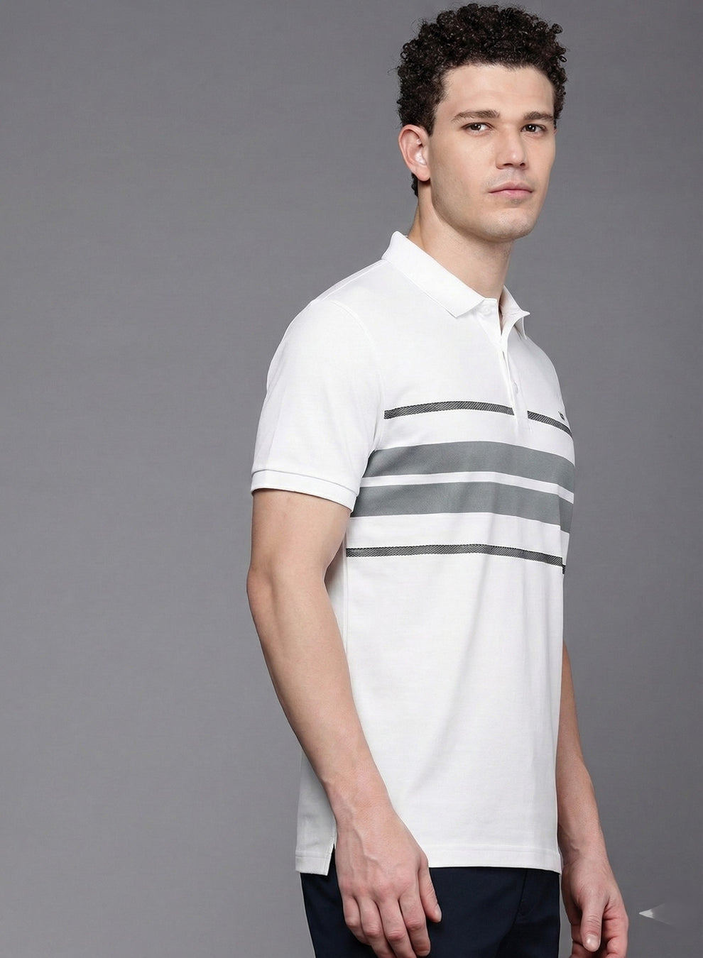 Man wearing a white polo shirt with gray stripes on a gray background